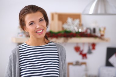 Mutfakta gülümseyen genç bir kadın, Noel arkaplanında soyutlanmış.