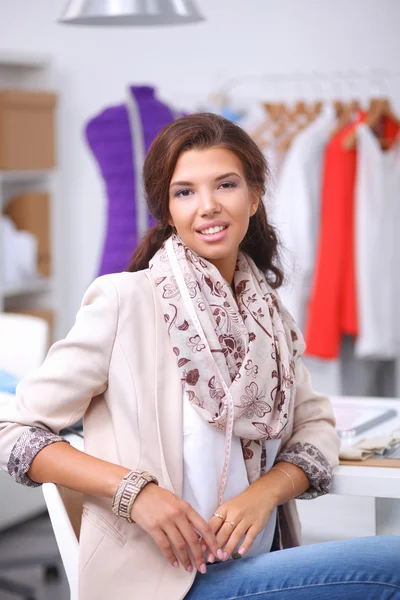 Lächelnde Modedesignerin sitzt am Schreibtisch — Stockfoto
