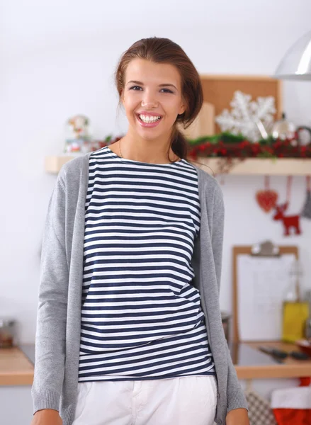 Mujer joven sonriente en la cocina, aislada en el fondo de Navidad —  Fotos de Stock