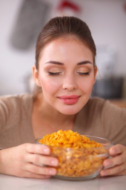 Gülümseyen çekici kadın mutfağın içinde kahvaltı yapıyor.