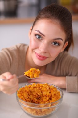 Gülümseyen çekici kadın mutfağın içinde kahvaltı yapıyor.
