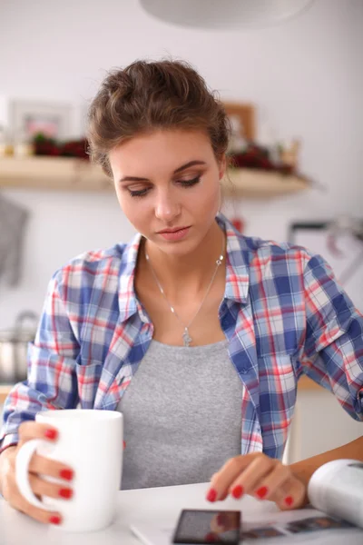 Mujer leyendo mgazine En la cocina en casa — Foto de Stock