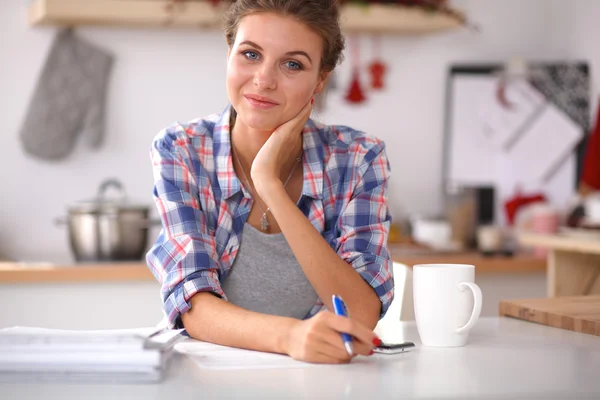 Fincan kahve ve gazete mutfak ile gülümseyen kadın — Stok fotoğraf