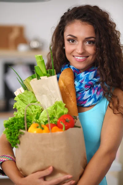 Young woman holding grocery shopping bag with vegetables Standing in the kitchen. — Stock Photo, Image