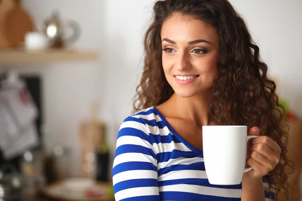 Retrato de mujer joven con taza contra fondo interior de la cocina. — Foto de Stock