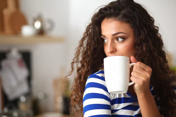 Retrato de mujer joven con taza contra fondo interior de la cocina. — Foto de Stock