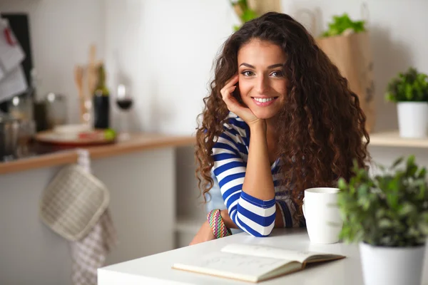 Sorridente giovane donna in cucina, isolata sullo sfondo — Foto Stock