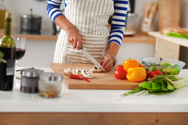 Mulher jovem cortando legumes na cozinha — Fotografia de Stock