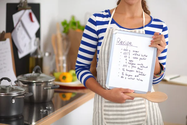 Kvinna i köket hemma, stående nära skrivbord med mapp — Stockfoto