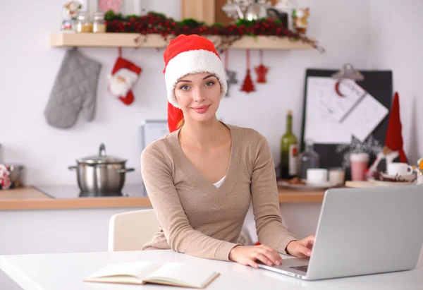 Smiling young woman in the kitchen, isolated on christmas background — Stock Photo, Image