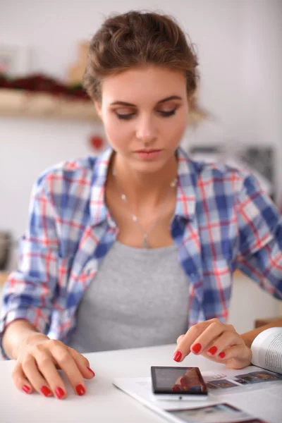 Mujer sonriente compras en línea utilizando la computadora y la tarjeta de crédito en la cocina — Foto de Stock