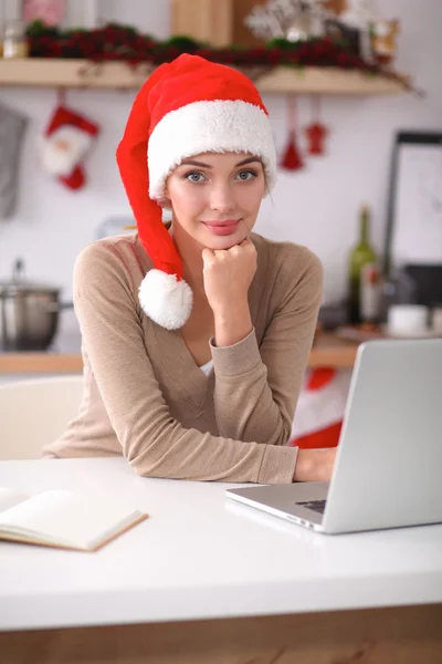 Glimlachende jonge vrouw in de keuken, geïsoleerd op kerst achtergrond — Stockfoto
