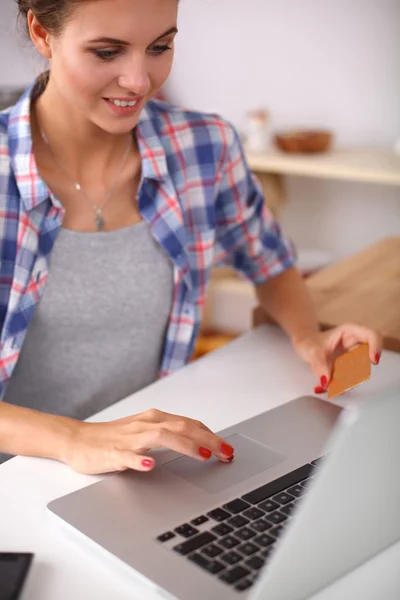 Mulher sorrindo compras on-line usando computador e cartão de crédito na cozinha — Fotografia de Stock
