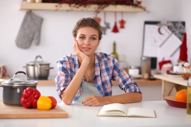 Mutfakta gülümseyen genç bir kadın, Noel arkaplanında soyutlanmış.
