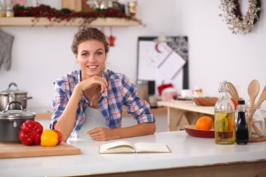 Mutfakta gülümseyen genç bir kadın, Noel arkaplanında soyutlanmış.