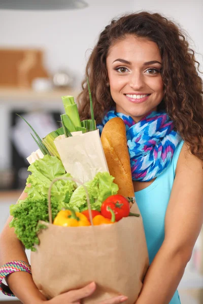 Junge Frau hält Einkaufstüte mit Gemüse in der Küche. — Stockfoto