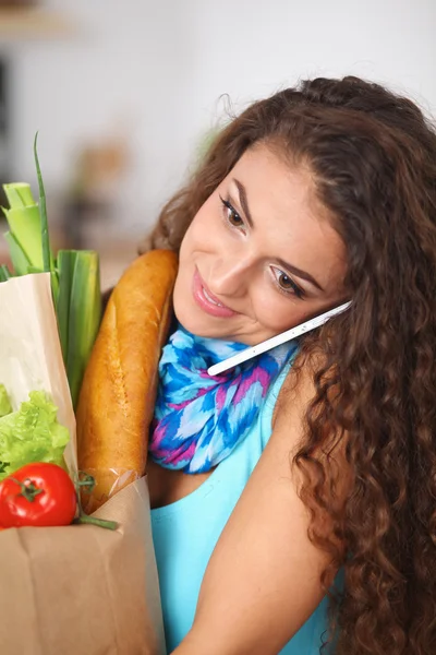 Young woman holding grocery shopping bag with vegetables Standing in the kitchen. — Stock Photo, Image