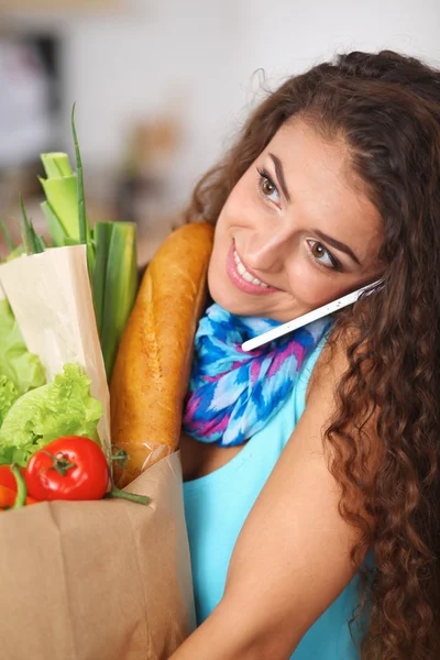 Young woman holding grocery shopping bag with vegetables Standing in the kitchen. — Stock Photo, Image