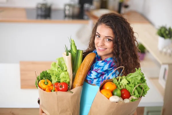 Young woman holding grocery shopping bag with vegetables Standing in the kitchen. — Stock Photo, Image