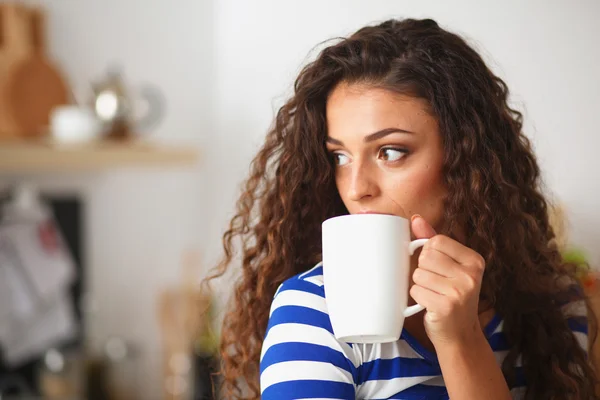 Retrato de mujer joven con taza contra fondo interior de la cocina. — Foto de Stock