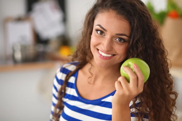 Feliz joven comiendo manzanas en la cocina — Foto de Stock