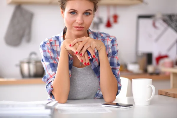 Donna sorridente con tazza di caffè e giornale in cucina — Foto Stock