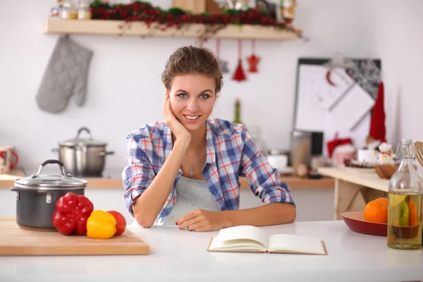 Leende ung kvinna i köket, isolerad på jul bakgrund — Stockfoto