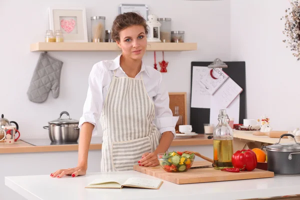 Glimlachende jonge vrouw in de keuken, geïsoleerd op kerst achtergrond — Stockfoto