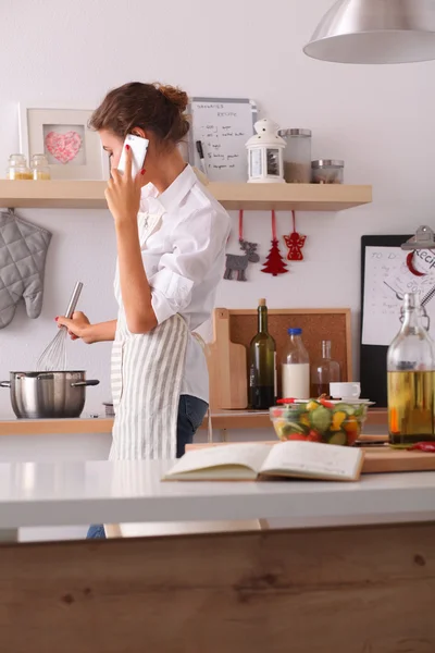 Portret van een lachende vrouw sms 'en van groenten in de keuken thuis — Stockfoto