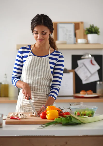 Jonge vrouw snijden groenten in de keuken — Stockfoto