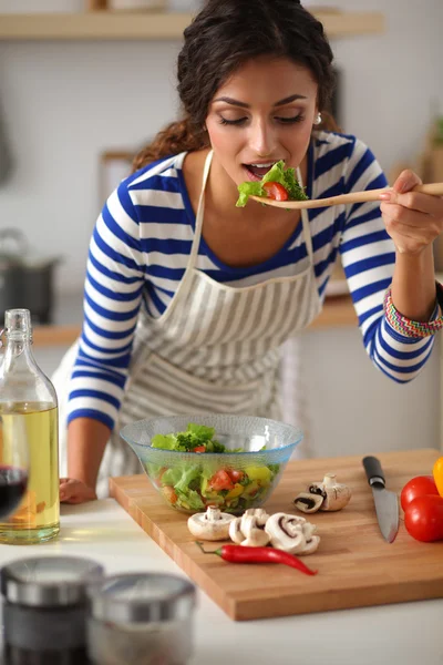 在现代厨房里吃新鲜沙拉的年轻女人 — 图库照片