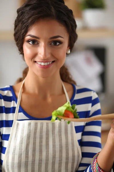 Молодая женщина ест свежий салат на современной кухне — стоковое фото