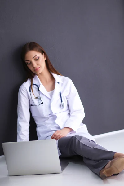 Doctor sitting on the floor near wall  with laptop — Stock Photo, Image