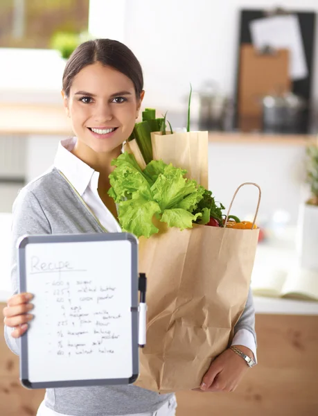 年轻女子捧着蔬菜任命杂货店购物袋 — 图库照片