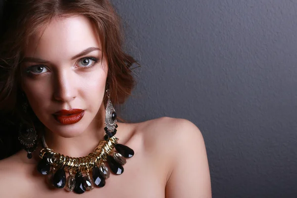 Portrait of young beautiful brunette woman in ear-rings, beads — Stock Photo, Image