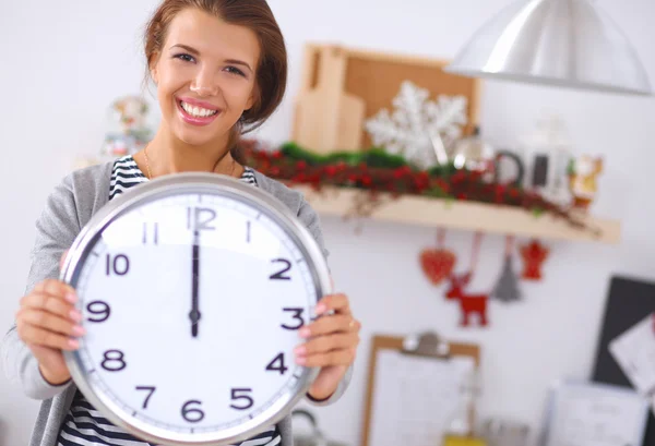 Happy young woman showing clock in christmas decorated kitchen — Stock Photo, Image