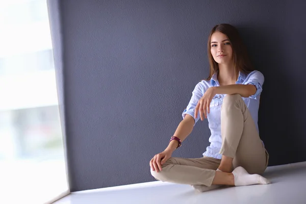 Mujer joven sentada en el suelo cerca de la pared oscura — Foto de Stock