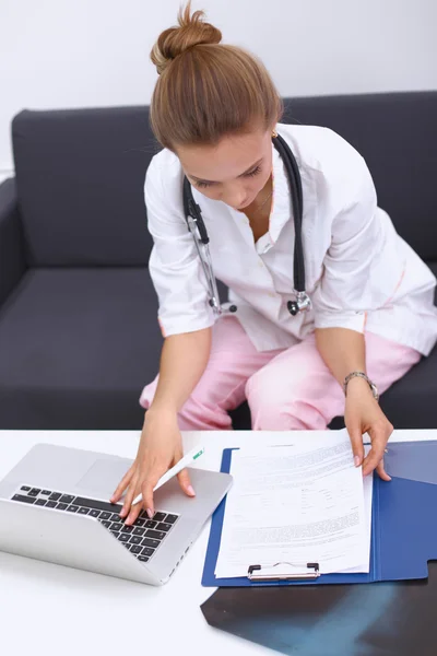 A female doctor filling in casebook at desk isolated on white — Stock Photo, Image