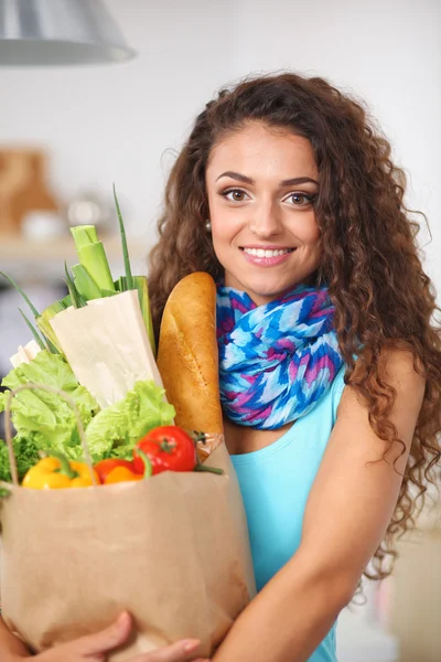 Young woman holding grocery shopping bag with vegetables Standing in the kitchen. — Stock Photo, Image