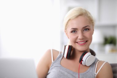 Evdeki genç ve güzel kadın kanepede oturup müzik dinliyor.
