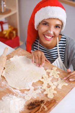Mutlu genç bayan gülümsüyor Noel hazırlıklarıyla eğleniyor Noel Baba şapkası takıyor.