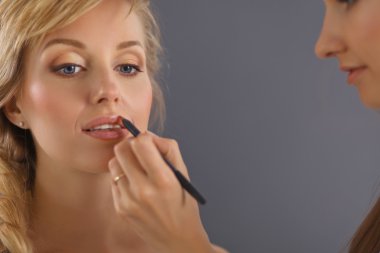 Kadından profesyonel makyaj yapan sanatçı.