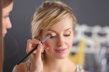 Kadından profesyonel makyaj yapan sanatçı.