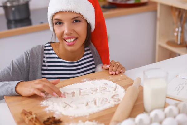 Lykkelig ung kvinde smilende glad for at have det sjovt med juleforberedelser iført Santa hat - Stock-foto