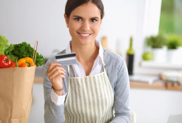 Lachende vrouw online winkelen met behulp van computer en creditcard in de keuken — Stockfoto