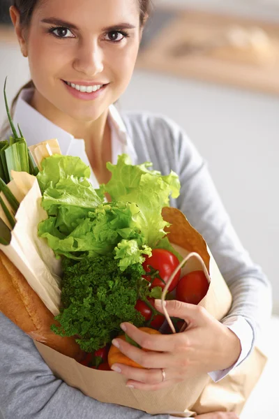 一个拿着蔬菜购物袋站在厨房里的年轻女人. — 图库照片