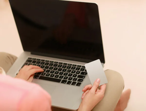 Ung kvinna sitter på thr golvet med laptop och hålla kreditkort. — Stockfoto
