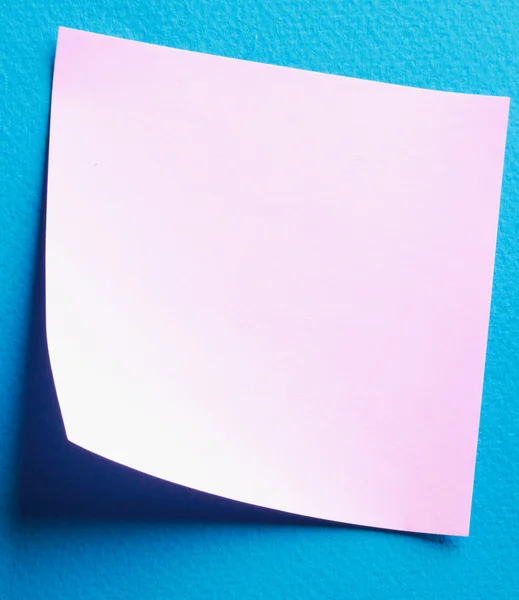 Papel rosa nota sobre fundo azul — Fotografia de Stock
