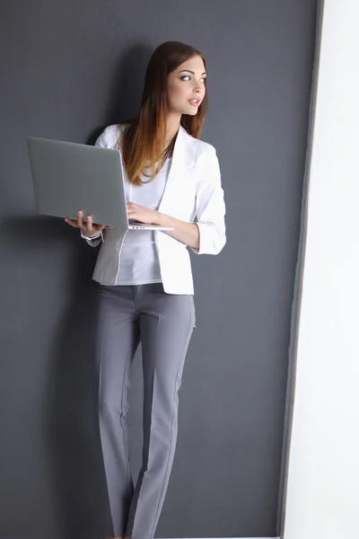 Mladá žena drží notebook, izolovaných na šedém pozadí — Stock fotografie