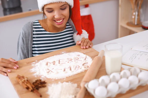 Lykkelig ung kvinde smilende glad for at have det sjovt med juleforberedelser iført Santa hat - Stock-foto